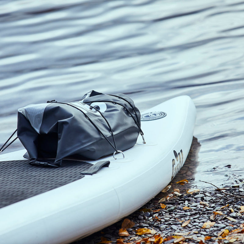 Lifestyle image of the 50L Gill Voyager Drybag in black, attached to front of a paddleboard.