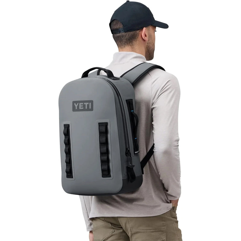 Person wearing a YETI backpack on a white background